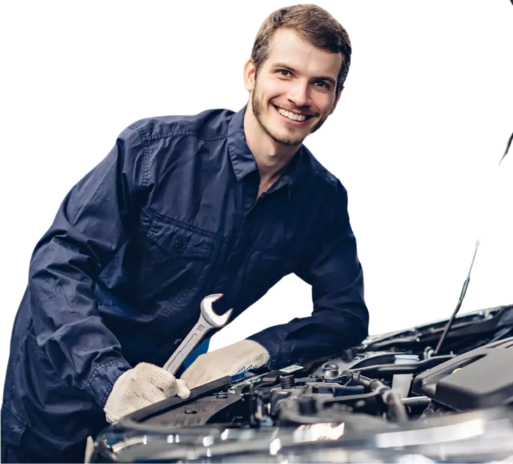 Glunderende autotechnicus die aan een voertuig werkt in een moderne reparatiewerkplaats met autoliften op de achtergrond.