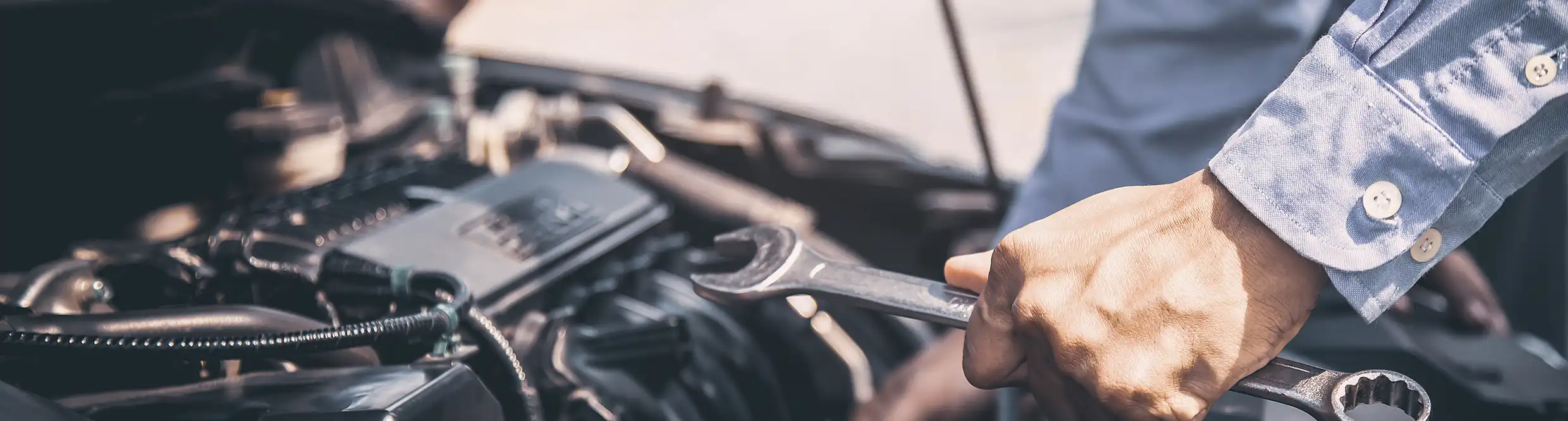 Autotechnicus die motoronderdelen onderhoudt met handgereedschap tijdens routinematig voertuigonderhoud.